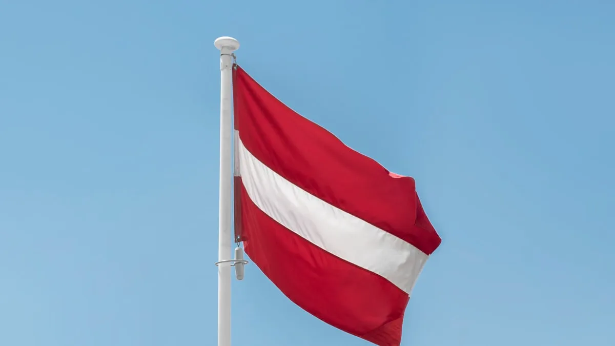 The flag of Austria waving against a blue sky