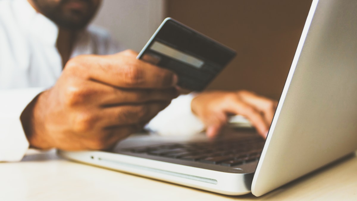 Person paying online with a credit card and a laptop